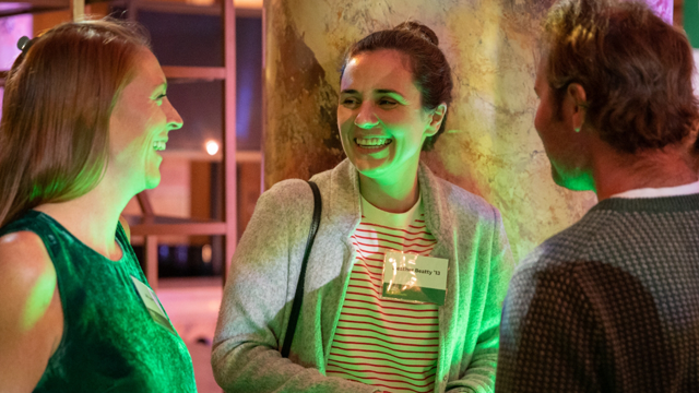 A woman facing two people and talking at an event